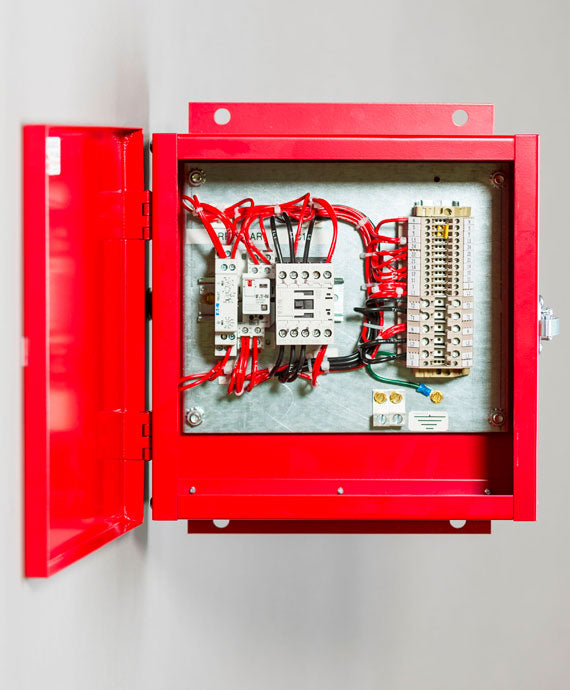 An open Life Safety Panel by Eaton, mounted on a wall, reveals neatly organized wires, switches, and circuits inside, including a motor-rated contactor. The door of the panel is open, showcasing its internal components and precise wiring.