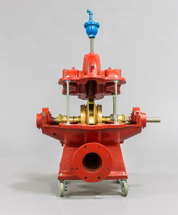 The Patterson Horizontal and Inline Fire Pump Parts, characterized by a large red metallic body with visible internal components, showcases a striking blue valve on top. Elegantly mounted on wheels, it stands out against a neutral gray background.